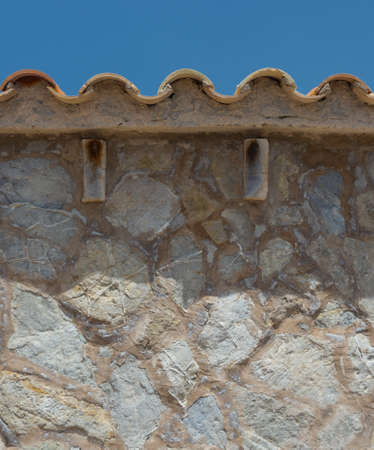 House detail - wall of natural stone and tiled terracotta roof. Typical for Mallorca, Balearic islands, Spain.の写真素材