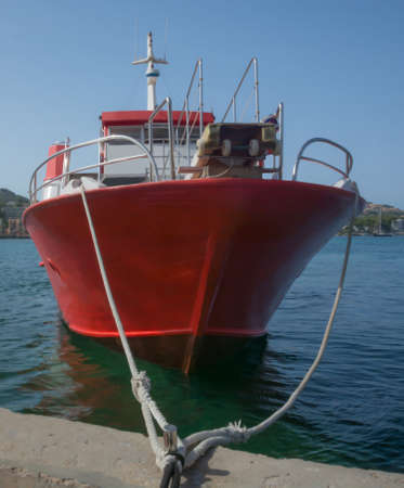 Red boat moored on quay in Mediterranean green water.の写真素材