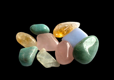 Semi-precious gemstones in yellow, green and pink, isolated on black. Quartz, aventurine, calcite,...