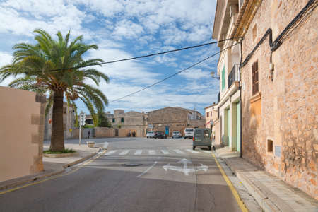 Santanyi, Majorca, Spain - November 2 2013: Sunny street view, palm tree and small parking lot with a few cars on November 2 2013 in Santanyi, Majorca, Balearic islands, Spainのeditorial素材