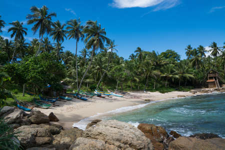 Tropical rocky beach with coconut palm trees, sandy beach and traditional fishing boats. Rocky Point, Tangalle, Southern Province, Sri Lanka, Asia.のeditorial素材