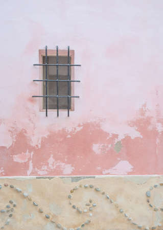 Pink house with black iron window and decorative friese with little pebbles in yellow ochre.の写真素材