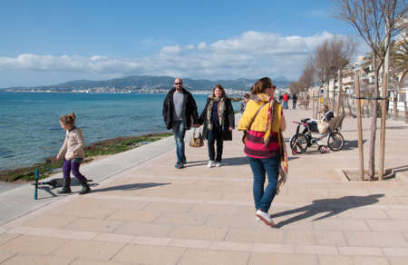 MOLINAR, MALLORCA, SPAIN - FEBRUARY 16, 2013: People spend a sunny winter day in the sun, walking along the Mediterranean coast on February 16 2013 in Molinar, Palma de Mallorca, Spain.のeditorial素材