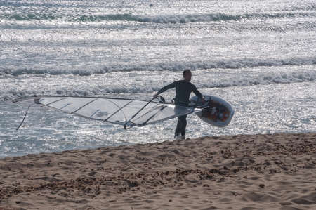 CAN PASTILLA, MAJORCA, SPAIN - FEBRUARY 10 2013: Wind surfer with his board on his way up on a sunny...