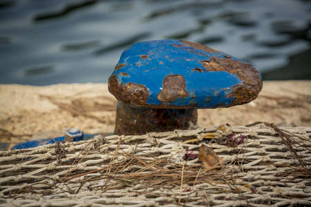 Blue Mooring Knob Close-up with rust and flaky paint with fishnet on a jetty, Mallorca, Balearic...