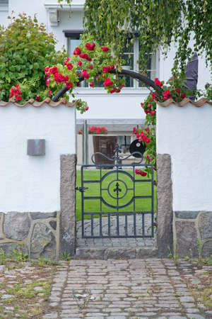AHUS, SOUTH SWEDEN - JUNE 28, 2014: Pretty home entrance with white washed wall and roses on June 28, 2013 in Ahus, South Sweden.のeditorial素材