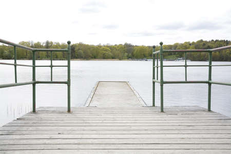 Wood pier with iron railing by lake, Stockholm, Sweden.