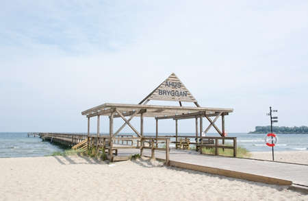 AHUS, SOUTH SWEDEN - JUNE 28, 2014: Ahus beach with flags and pier on June 28, 2014 in Ahus, South Sweden.のeditorial素材