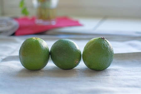 Three lime fruits in a row on linen towel.の写真素材
