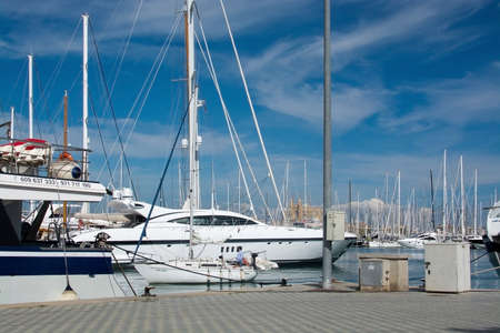 PALMA DE MALLORCA SPAIN  APRIL 19 2015: Midsize sailboat entering harbor with huge expensive yachts and tour boats on April 19 2015 in Palma de Mallorca Balearic islands Spain.のeditorial素材