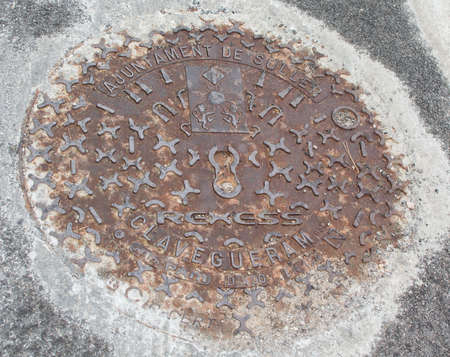 PORT DE SOLLER, MALLORCA, SPAIN - APRIL 22, 2015: Rusty lid emblem on street well or manhole cover on April 22, 2015 in Port de Soller, Mallorca, Balearic islands, Spain.のeditorial素材