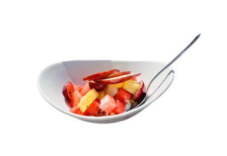 Fruit salad in plate with spoon isolated on white.の写真素材