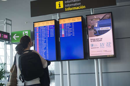 PALMA MALLORCA SPAIN  APRIL 24 2015: Woman reading departure information sign in Palma Son Sant Joan International airport on April 24 2015 in Palma de Mallorca Spain.のeditorial素材