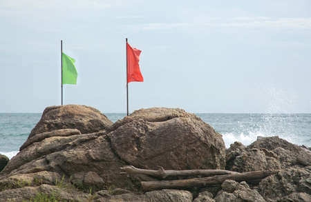 Green and red flag on a rock by a beach in Sri Lanka Asia.の写真素材