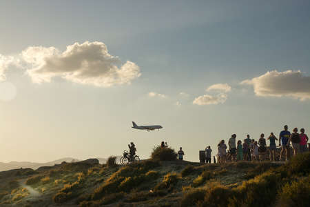 CAN PASTILLA, MAJORCA - JULY 21, 2014: People enjoy airplane spotting in golden sunset skies in a sunny summer evening in Es Carnatge on July 21, 2014 in Can Pastilla, Majorca, Spain.のeditorial素材