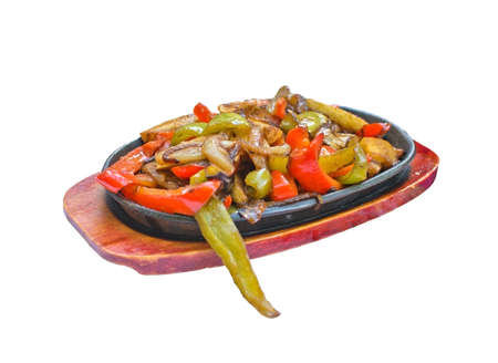 Plate with fried Tex Mex vegetables such as onion and peppers on wood and black iron plates isolated on whiteの写真素材