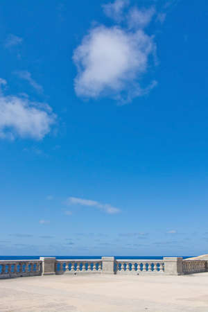 Sparse image of classical stone railing, horizon and blue sky with light summer clouds on a sunny day, Malta.の写真素材