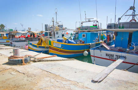 MARSAXLOKK, MALTA - SEPTEMBER 15, 2015: Colorfully painted small wooden boats moored along the quay...