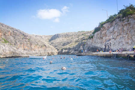 BLUE GROTTO, MALTA - SEPTEMBER 15, 2015: Pier with tourists and boats ready to go on tour in popular tourist attraction Blue Grotto on a sunny day in September 15, 2015 in Malta.のeditorial素材