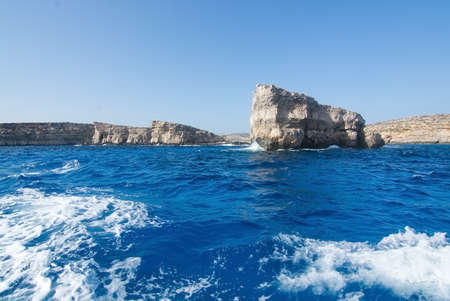 Limestone rock with caves and blue Mediterranean ocean water near Comino island, Malta.