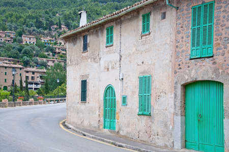 DEIA, MALLORCA, SPAIN - JULY 3, 2011: Curvy road around a building with green window shutters on an overcast day on July 3, 2011 in Deia, Mallorca, Balearic islands, Spain.のeditorial素材