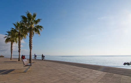 PALMA DE MALLORCA, BALEARIC ISLANDS, SPAIN - DECEMBER 22, 2015: People on feet and wheels on the Molinar boardwalk by the Mediterranean ocean in afternoon sunlight on December 22, 2015 in Palma de Mallorca, Balearic islands, Spainのeditorial素材