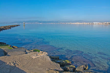 Morning tranquil beach with rocks, lighthouse and turquoise transparent water in Playa de Palma, Mallorca, Balearic islands, Spainの写真素材
