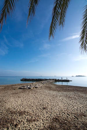 IBIZA, SPAIN - DECEMBER 17, 2015: Beach landscape with sea horizon and two people on stone pier on December 17, 2015 in Ibiza, Balearic islands, Spainのeditorial素材