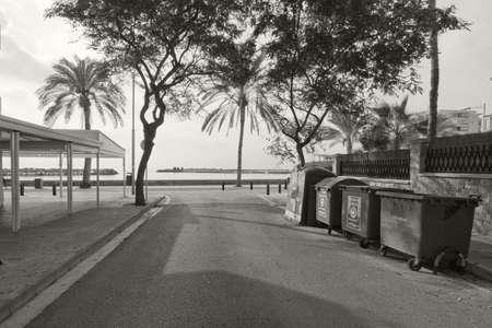 CAN PASTILLA, MALLORCA, BALEARIC ISLANDS, SPAIN - DECEMBER 14, 2015: Quiet empty seaside street and garbage containers monochrome sepia image on December 14, 2015 in Balearic islands, Spainのeditorial素材