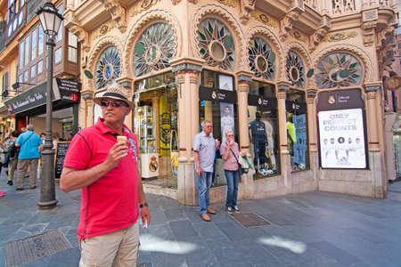 PALMA DE MALLORCA, BALEARIC ISLANDS, SPAIN - APRIL 13, 2016: Man in red shirt, hat and sunshades enjoys an icecream in front of Real Madrid store in beautiful Can Corbella art nouveau building, housing the Real Madrid sports store, in Palma de Mallorca, Bのeditorial素材