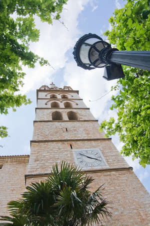 BINISSALEM, MALLORCA, BALEARIC ISLANDS, SPAIN - MAY 19, 2016: Church tower with clock and lamp in...