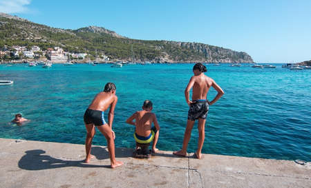 SANT ELM, MALLORCA, SPAIN - AUGUST 5, 2016: Three boys playing on the quay on a sunny summer day in August 5 in Sant Elm, Mallorca, Spain.のeditorial素材
