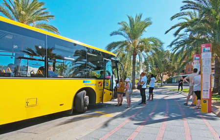 SANTA PONSA, MALLORCA, SPAIN - SEPTEMBER 6, 2016:  Passengers boarding a yellow regional bus TIB at a bus stop on a sunny day on September 6, 2016 in Santa Ponsa, Mallorca, Spain.のeditorial素材