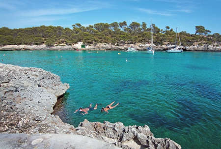 CALA MONDRAGO, MALLORCA, SPAIN - SEPTEMBER 4, 2016: Couple snorkeling in clear turquoise water on a sunny day on September 4, 2016 in Cala Mondrago, Mallorca, Spain.のeditorial素材