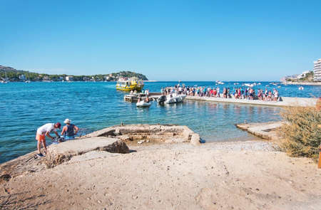 SANTA PONSA, MALLORCA, SPAIN - SEPTEMBER 6, 2016: People fish and stand in line for a boat ride on a sunny day on September 6, 2016 in Santa Ponsa, Mallorca, Spain.のeditorial素材