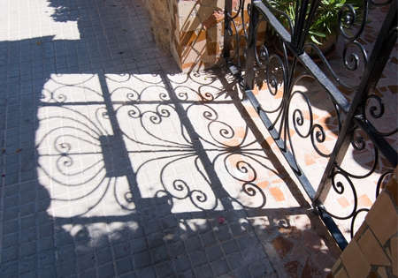 CALA FORNELLS, MALLORCA, SPAIN - SEPTEMBER 6, 2016: Beautiful shadow play from wrought iron fence on a sunny day on September 6, 2016 in Cala Fornells, Mallorca, Spain.のeditorial素材
