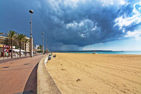 CAN PASTILLA, MALLORCA, BALEARIC ISLANDS, SPAIN - SEPTEMBER 30, 2016: Yellow volleyball nets and players on the beach with dark cloud of thunderstorm and rain approaching on September 30, 2016 in Can Pastilla, Mallorca, Balearic islands, Spain.のeditorial素材