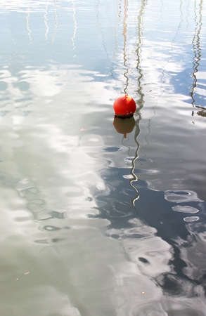 Red buoy in marina and masts reflections and skies in green harbor water, Mallorca, Spain.の写真素材