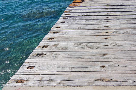 Rustic wood pier with nails and clear green water background texture