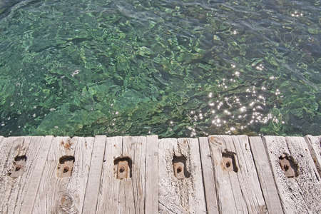 Rustic wood pier with nails and clear green water background textureの写真素材