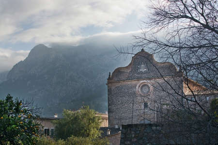 SOLLER, MALLORCA, SPAIN - JANUARY 3, 2017: Convent Sagrats Cors and landscape view with cloud topped mountain and chimney smoke on a sunny foggy winter morning on January 3, 2017 in Soller, Mallorca, Spain.のeditorial素材