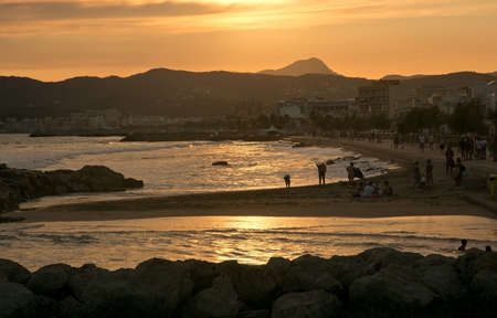 PALMA DE MALLORCA, BALEARIC ISLANDS, SPAIN - JUNE 29, 2017: Golden sunset over the Mediterranean and people at Molinar beach on a summer evening on June 29, 2017 in Palma de Mallorca, Balearic islands, Spain.のeditorial素材