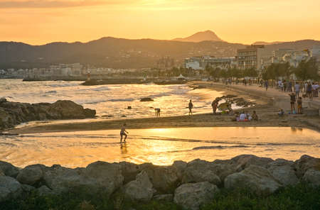 PALMA DE MALLORCA, BALEARIC ISLANDS, SPAIN - JUNE 29, 2017: Golden sunset over the Mediterranean and people at Molinar beach on a summer evening on June 29, 2017 in Palma de Mallorca, Balearic islands, Spain.のeditorial素材