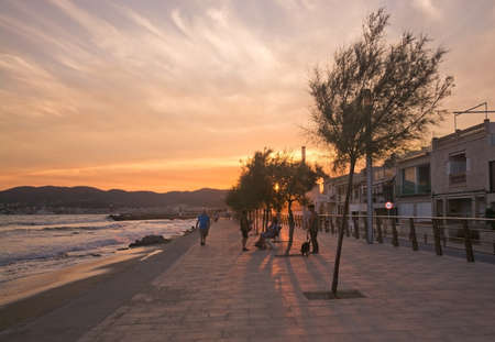PALMA DE MALLORCA, BALEARIC ISLANDS, SPAIN - JUNE 29, 2017: Sunny evening people walk their dogs at Molinar beach on a summer evening on June 29, 2017 in Palma de Mallorca, Balearic islands, Spain.のeditorial素材