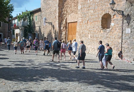 VALLDEMOSSA, MALLORCA, BALEARIC ISLANDS, SPAIN - JULY 26, 2017: Group of tourists on a village walk on a sunny day on July 26, 2017 in Valldemossa, Mallorca, Balearic islands, Spain.のeditorial素材