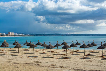 PLAYA DE PALMA, MALLORCA, SPAIN - DECEMBER 16, 2017: Parasols on winter beach on a windy day on December 16, 2017 in Mallorca, Balearic islands, Spainのeditorial素材