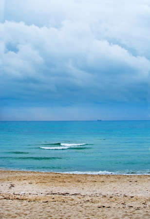Two waves cloudy sky, tranquility on Mediterranean winter beach and horizon with ship in Mallorca, Balearic islands, Spain in February.の写真素材