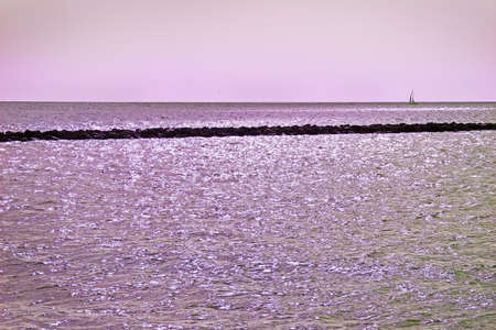 Simplicity in grey with ocean, horizon, pier and sailboat