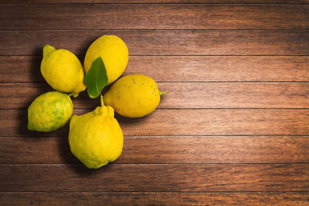 Lemons on caulked mahogany wood planks background texture closeup.