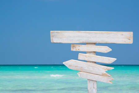White rustic wooden signpost with empty space for text on tropical sea landscape in azure turquoise and blueの写真素材